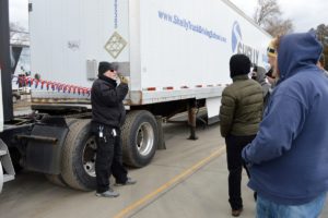 Truck driving instructor speaking to several students. 