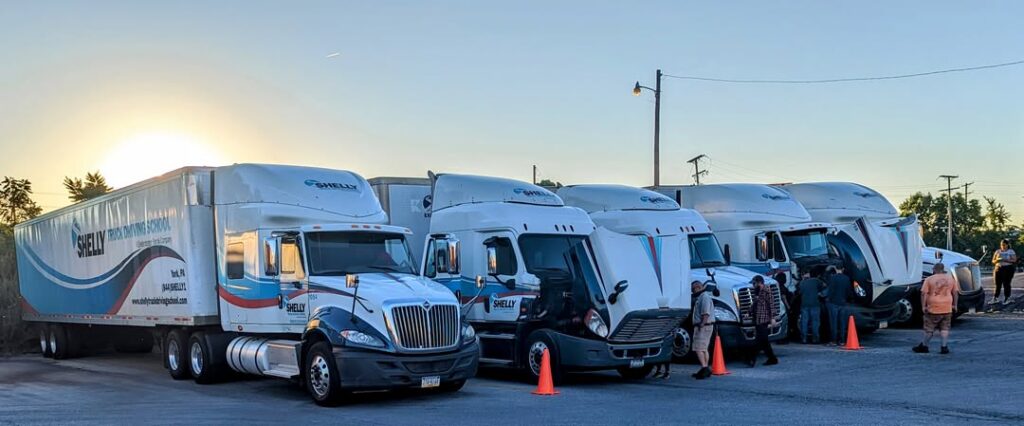 Truck driving school training trucks lined up in parking lot.