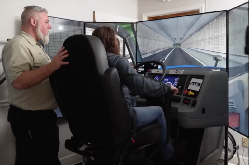 Truck driving student learning on the truck driving simulator with instructor supervision.